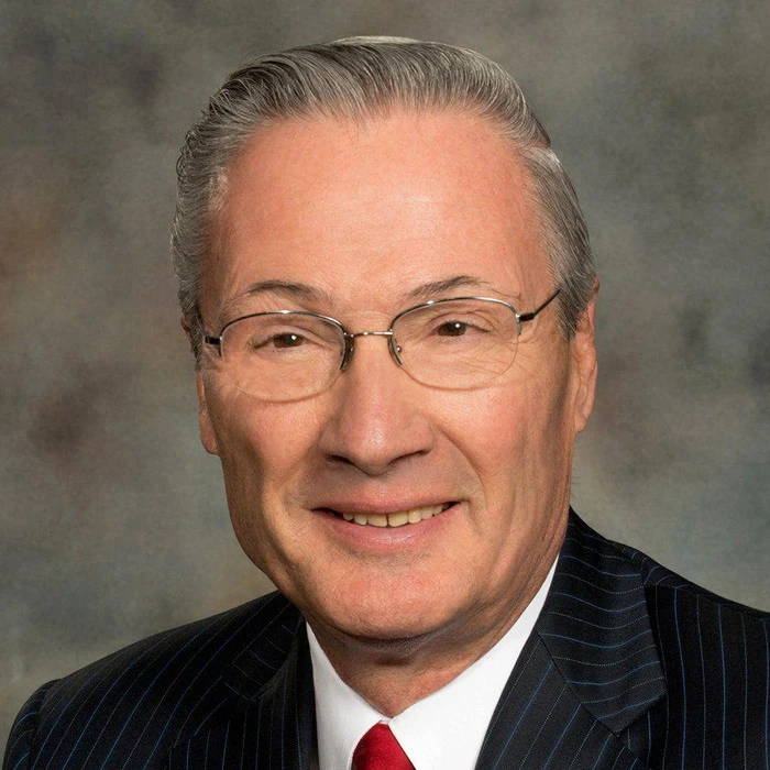 Hal Daub in a dark pinstripe suit and red tie