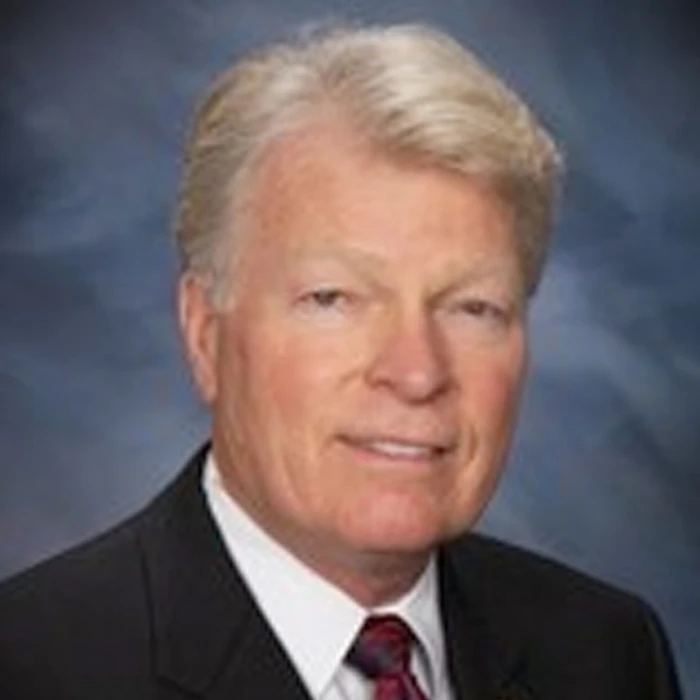 Lewis H. Wiens in a dark suit and burgundy tie