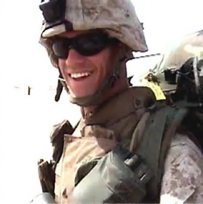 Corporal Jason L. Dunham smiling in desert camouflage, helmet and sunglasses